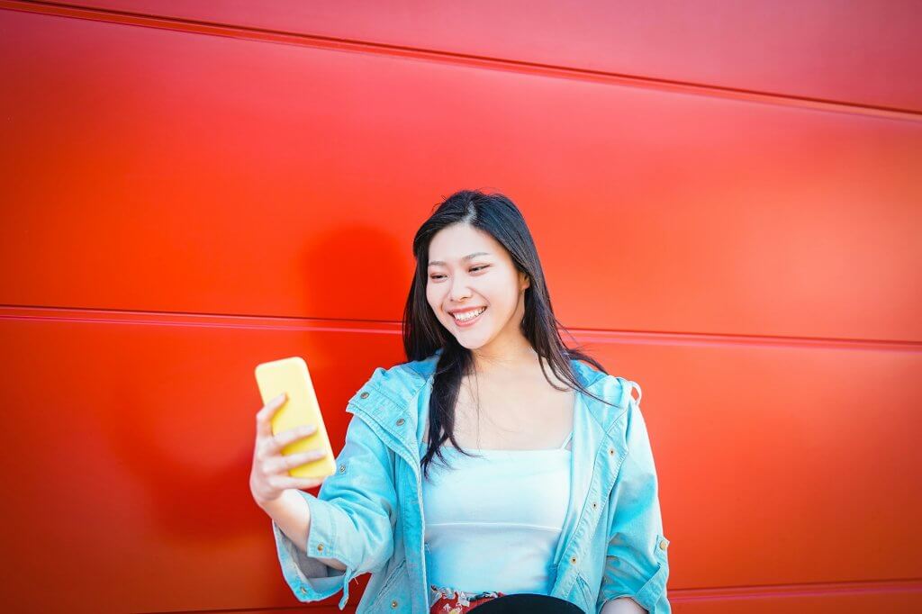 Happy asian influncer using mobile smart phone outdoor